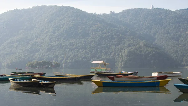 Pokhara, Nepal 'deki Phewa Gölü' nde arka planda dağlarla çevrili birkaç renkli tekneye bakın. Güneşli bir gün. Rahatlama ve sükunet, huzur ve sessizlik..