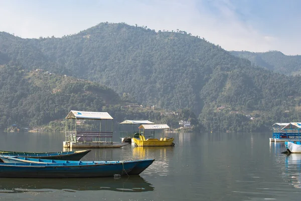 Pokhara, Nepal 'deki Phewa Gölü' nde arka planda dağlarla çevrili birkaç renkli tekneye bakın. Güneşli bir gün. Rahatlama ve sükunet, huzur ve sessizlik..