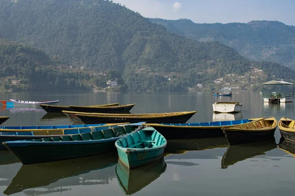 Pokhara, Nepal 'deki Phewa Gölü' nde arka planda dağlarla çevrili birkaç renkli tekneye bakın. Güneşli bir gün. Rahatlama ve sükunet, huzur ve sessizlik..