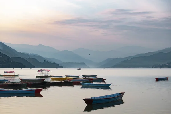 Pokhara, Nepal 'deki Phewa Gölü' nde arka planda dağlarla çevrili birkaç renkli tekneye bakın. Güneşli bir gün. Rahatlama ve sükunet, huzur ve sessizlik..
