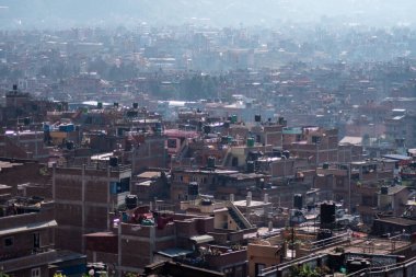 Bhaktapur, Katmandu, Nepal - 23 Aralık 2019: Tuğla evler ve kimliği belirlenemeyen insanlarla dolu çatılardan, bahçelerinden, bitkilerinden ve çamaşırlarından oluşan şehir manzarası 23 Aralık 2019 'da Bhaktapur, Katmandu, Nepal