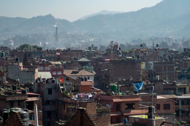 Bhaktapur, Katmandu, Nepal - 23 Aralık 2019: Tuğla evler ve kimliği belirlenemeyen insanlarla dolu çatılardan, bahçelerinden, bitkilerinden ve çamaşırlarından oluşan şehir manzarası 23 Aralık 2019 'da Bhaktapur, Katmandu, Nepal