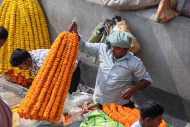 Kolkata, Hindistan - 2 Şubat 2020: Kimliği belirlenemeyen kişiler, Howrah Köprüsü yakınlarındaki Mallick Ghat çiçek pazarına katılıyor ve 2 Şubat 2020 'de Kolkata, Hindistan' da renkli kadife çiçekleri alıp satıyor.