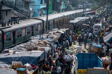 Kolkata, Hindistan - 2 Şubat 2020: Kimliği belirsiz insanlar Howrah köprüsündeki Mallick Ghat çiçek pazarına katılıyor ve 2 Şubat 2020 tarihinde Hindistan 'ın Kolkata kentinde bir tren geçiyor.
