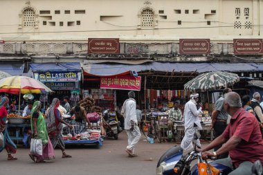 Puri, Hindistan - 3 Şubat 2020: Kimliği belirsiz insanlar 3 Şubat 2020 'de Puri, Hindistan' da ellerinde yiyecek, giyecek ve aksesuarlarla bir sokak marketinin önünden geçtiler.