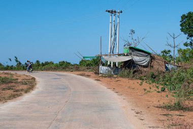 Chaung Thar, Myanmar - 26 Aralık 2019: İnsanlar 26 Aralık 2019 tarihinde Chaung Thar, Myanmar 'da asfalt bir yolda bir sokak restoranının önünden motosikletle geçtiler