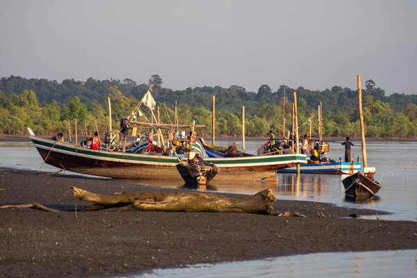 Chaung Thar, Myanmar - December 26, 2019: Traditional wooden boats by the shore of a river lit up by the sunset on December 26, 2019 in Chaung Thar, Myanmar