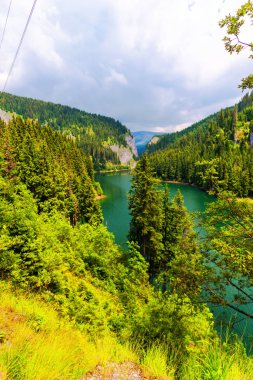 Yemyeşil ağaçlar ve sakin turkuaz Nehri ile yüksek dağları