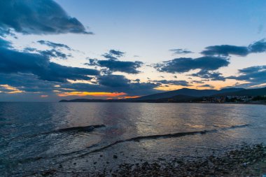 Çakıl taşları ve gün batımı arka plan ile deniz kıyısı