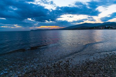 Çakıl taşları ve gün batımı arka plan ile deniz kıyısı