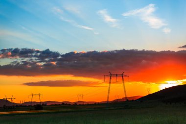 görkemli turuncu kırmızı günbatımı gökyüzü ve elektrik direkleri