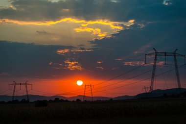 Güneş ve gökyüzü, gün batımı alanındaki elektrik direkleri 
