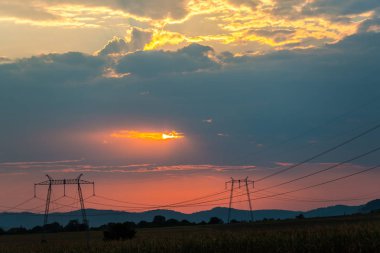 günbatımı gökyüzünde, alandaki elektrik direkleri 