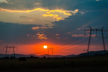 Güneş ve gökyüzü, gün batımı alanındaki elektrik direkleri 