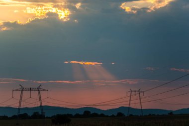 Turuncu günbatımı gökyüzü arka plan ile alanda elektrik direkleri.