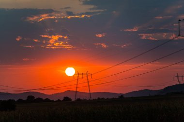 Güneş ve gökyüzü, gün batımı alanındaki elektrik direkleri 