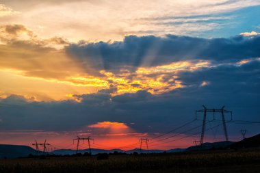 günbatımı gökyüzünde, alandaki elektrik direkleri 