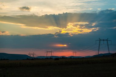 günbatımı gökyüzünde, alandaki elektrik direkleri 