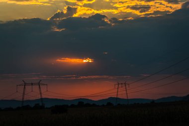 günbatımı gökyüzünde, alandaki elektrik direkleri 