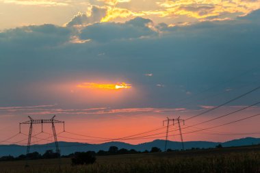 günbatımı gökyüzünde, alandaki elektrik direkleri 