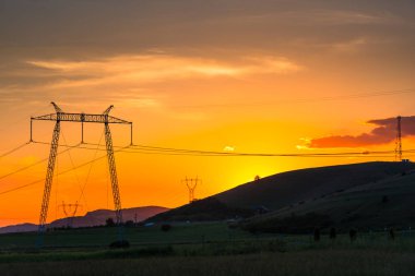görkemli turuncu kırmızı günbatımı gökyüzü ve elektrik direkleri 
