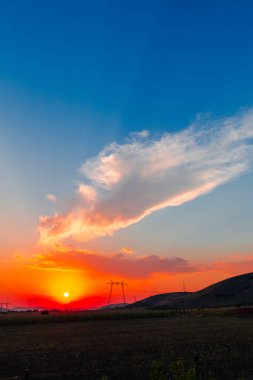 görkemli kırmızı günbatımı gökyüzü ve alandaki elektrik direkleri