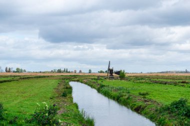 Alanları ve nehir ile küçük ahşap yel değirmeni