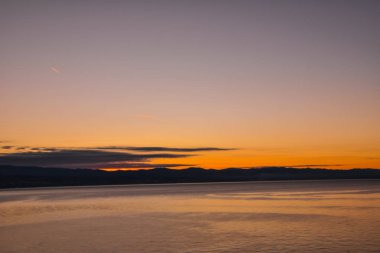 Alacakaranlık turuncu günbatımı gökyüzü ve tepeler ve göl su 