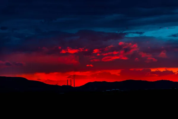 Vermelho Majestoso Céu Por Sol Montanhas Silhuetas Com Torres Fábrica — Fotografia de Stock