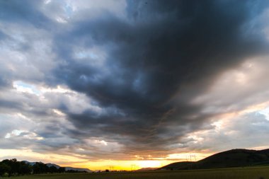 Gün batımı gökyüzü arka plan ile alanda elektrik direkleri.