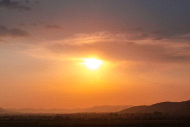 Arka planda parlayan gün batımı ile alan