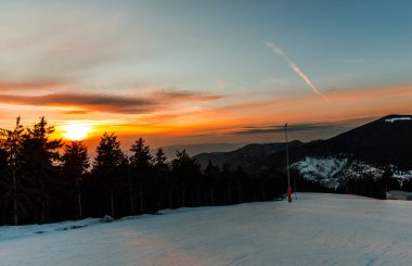 karda turuncu günbatımı gökyüzü dağlar ağaçları ile kaplı 