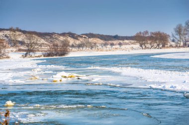 İki çıplak ağaçlar ile kışın donmuş nehir