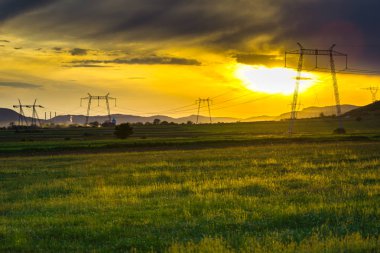 günbatımı gökyüzünde, alandaki elektrik direkleri 