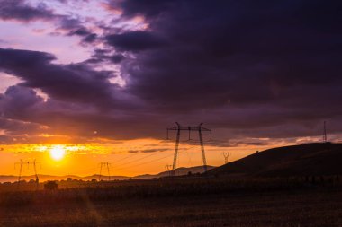 Gün batımı gökyüzü arka plan üzerinde elektrik direkleri ile Alan