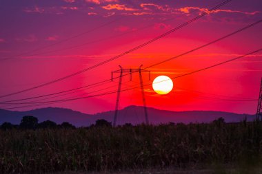 parlak kırmızı güneş ve gökyüzünde, elektrik direkleri iletim günbatımı