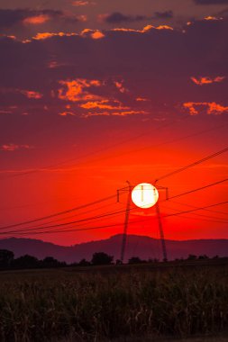görkemli kırmızı günbatımı gökyüzü ve alandaki elektrik direkleri 