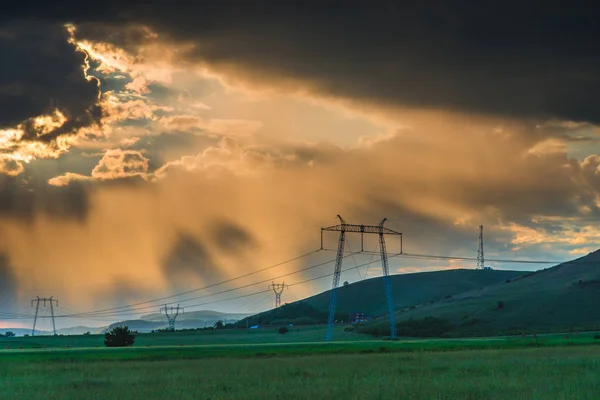 cloudy sunset sky above field with electric poles in field