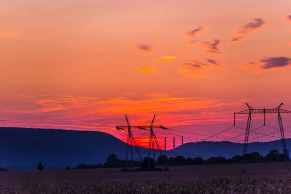 Field with electric poles on sunset sky background