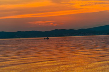 görkemli turuncu kırmızı günbatımı gökyüzü ve balıkçı teknesi su 
