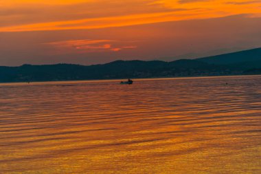 görkemli turuncu kırmızı günbatımı gökyüzü ve balıkçı teknesi su 