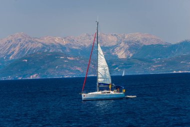 zemin üzerine mavi deniz suyu ve dağlar Yelkenli tekne 