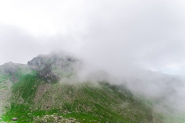 gri bulutların üzerinde dağ tepe yeşil çayır çimen 