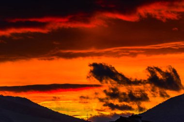 görkemli turuncu günbatımı gökyüzü bulutlar ve tepeler ile 