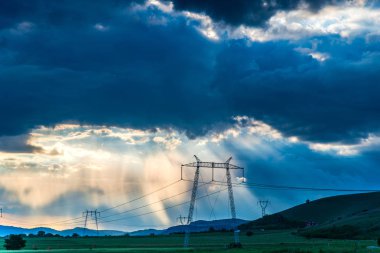 bulutlu gün batımı gökyüzü güneş ışınları ve elektrik direkleri ile alanında kuleleri 
