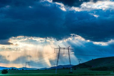 bulutlu gün batımı gökyüzü güneş ışınları ve elektrik direkleri ile alanında kuleleri 