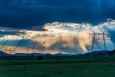 bulutlu gün batımı gökyüzü güneş ışınları ve elektrik direkleri ile alanında kuleleri 