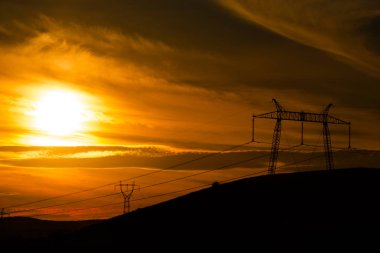 Elektrik direkleri ve gün batımı gökyüzü arka plan ile Alan