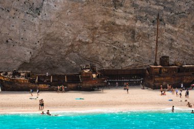 İnsanlar eski terk edilmiş gemi, Yunanistan ile plajda dinlenme.