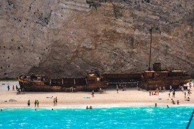 İnsanlar eski terk edilmiş gemi, Yunanistan ile plajda dinlenme.